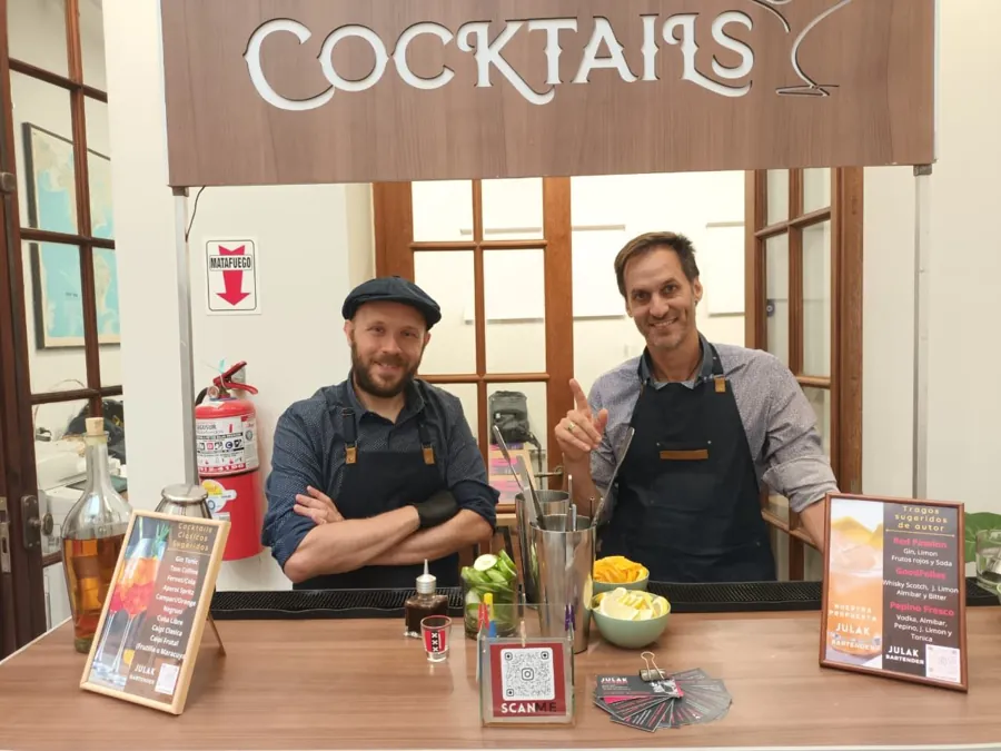 Dos bartenders sonriendo detrás de la barra de tragos en un cumpleaños