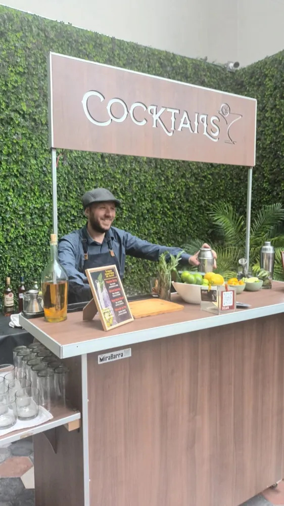 Barra móvil de tragos montada frente a una pared verde