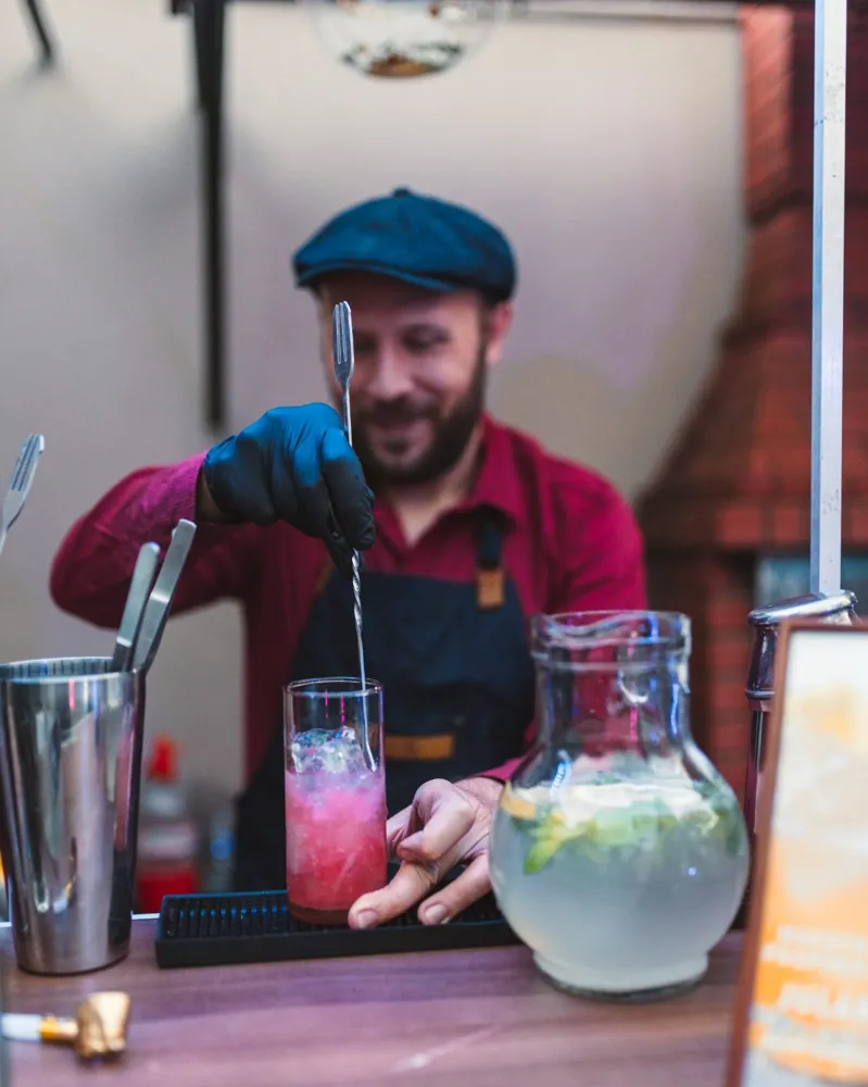 Trago rosado con hielo picado preparado con cuchara de bar